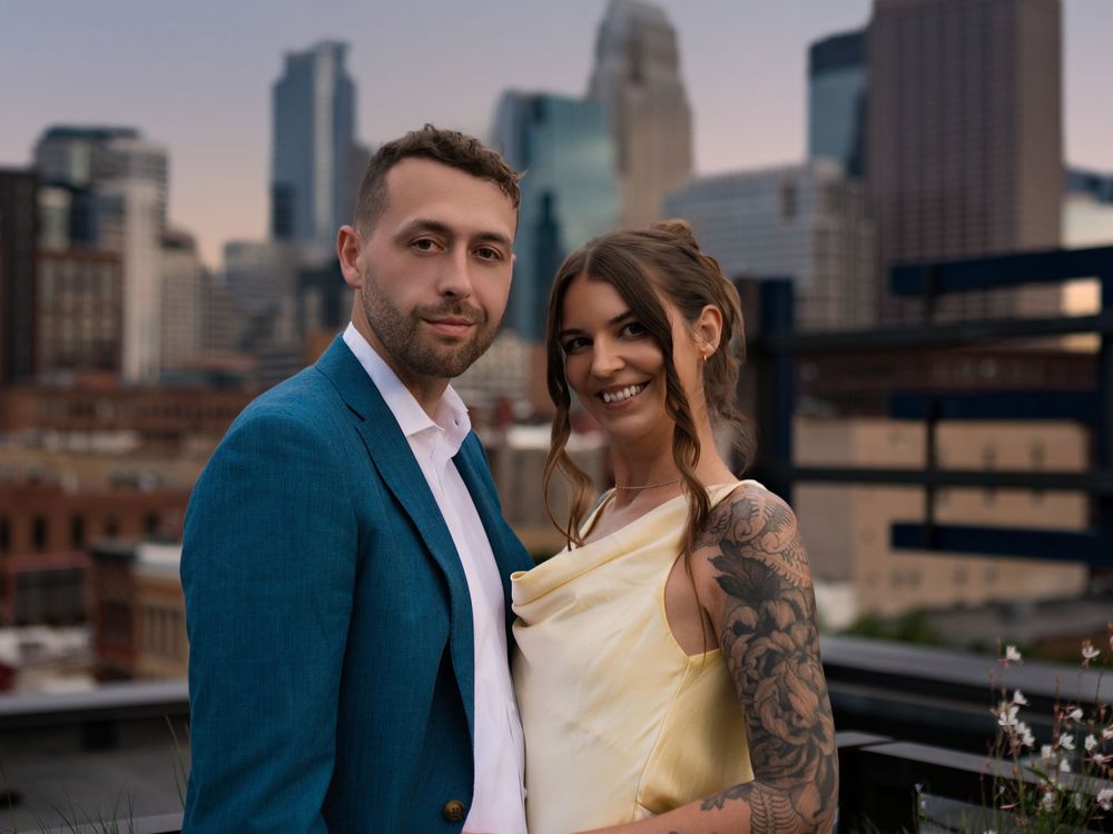 A couple on a rooftop at dusk with the Minneapolis skyline behind them