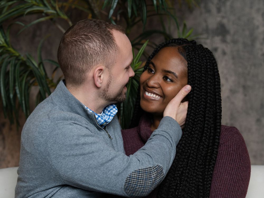 A man gently touching a smiling woman's cheek during an indoor couples session