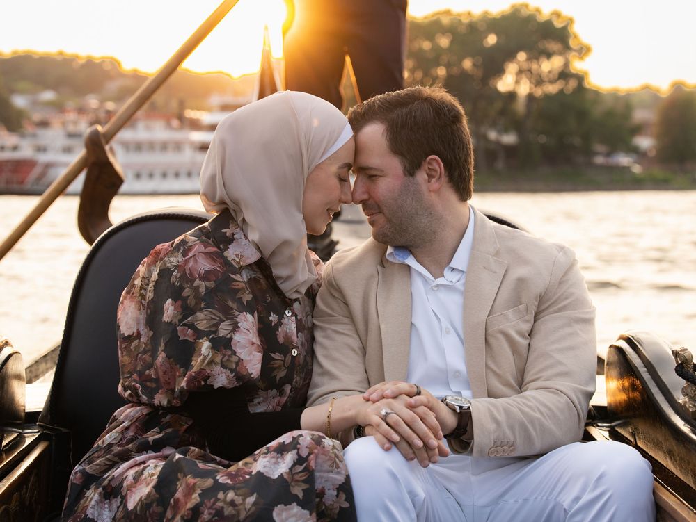 A couple touching foreheads on a gondola ride along a river at sunset