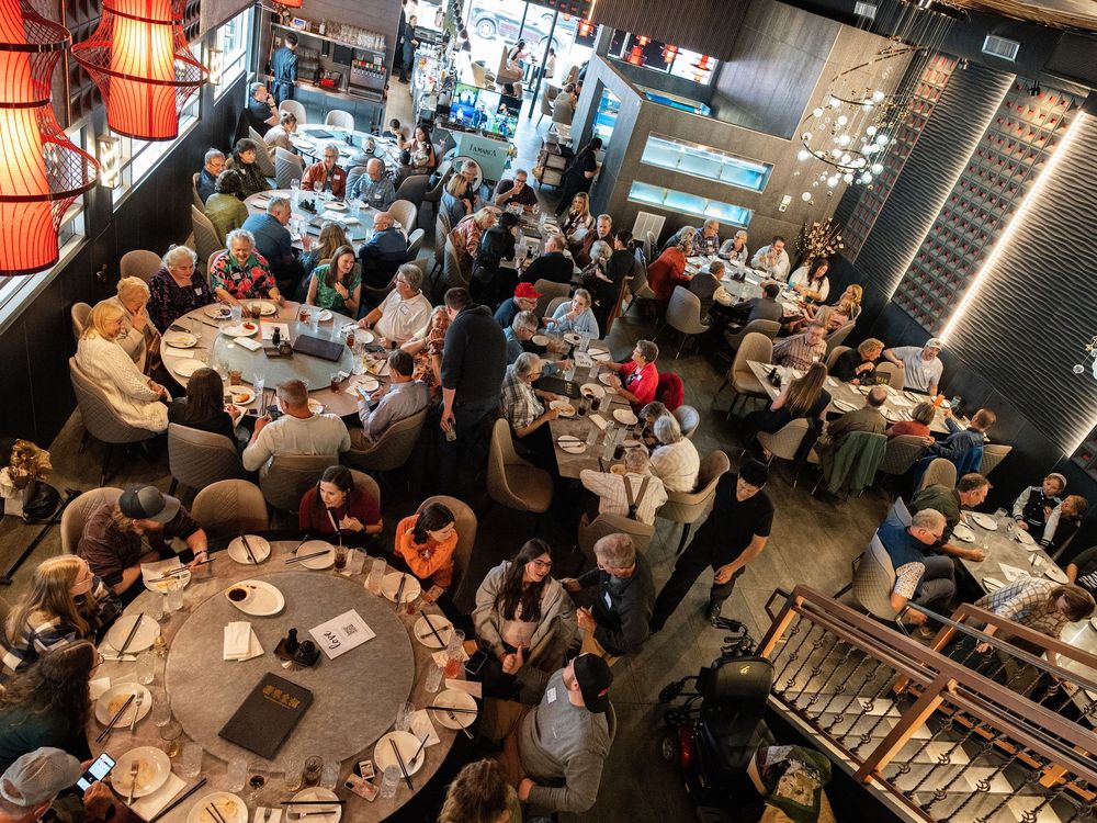 An overhead view of guests seated at round tables during a busy restaurant event