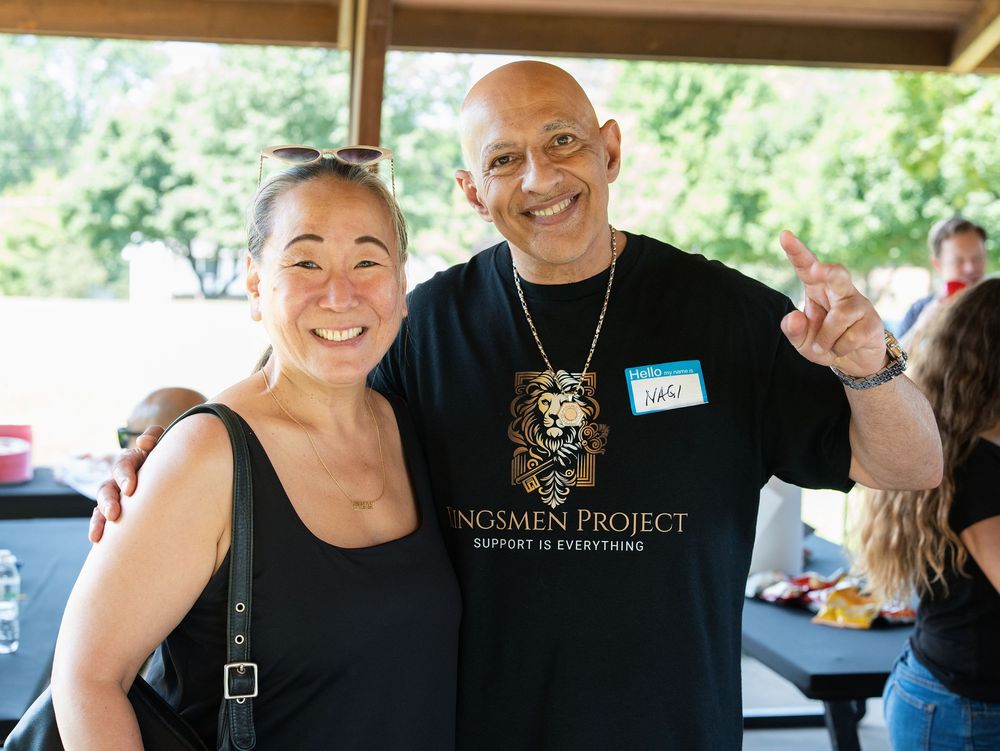 A smiling man and woman posing together at an outdoor community gathering