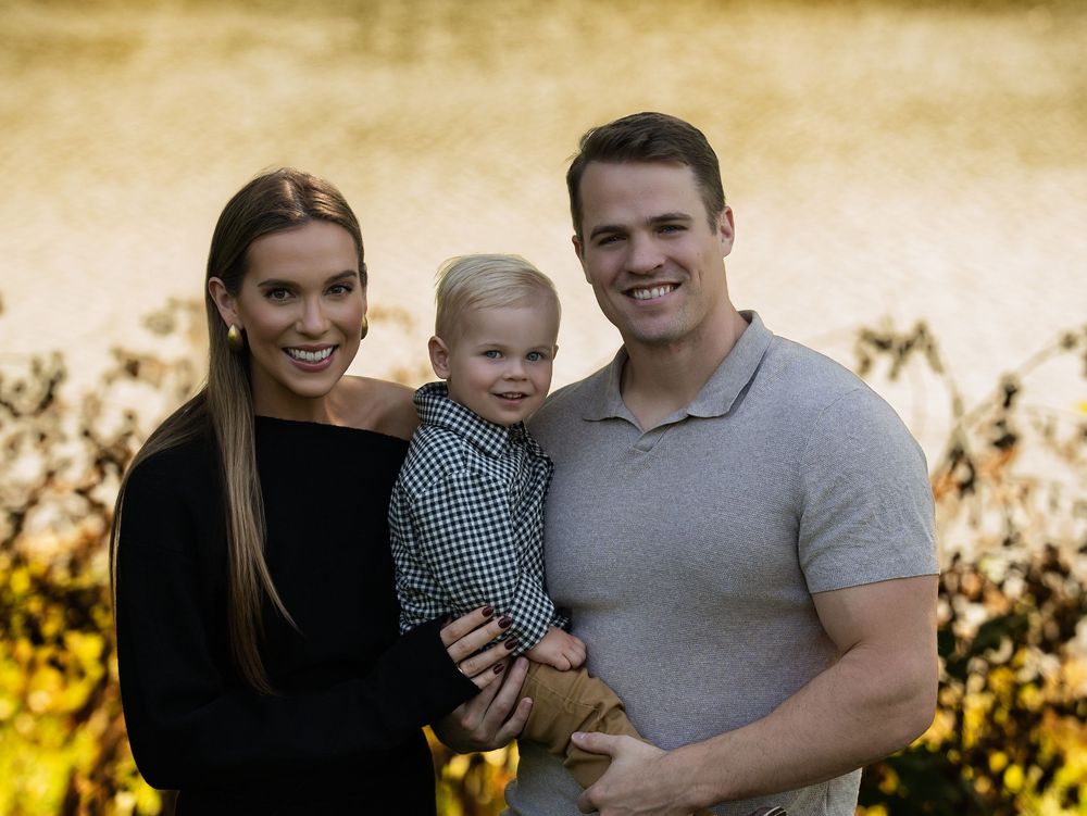Parents holding their young son against a soft golden autumn background