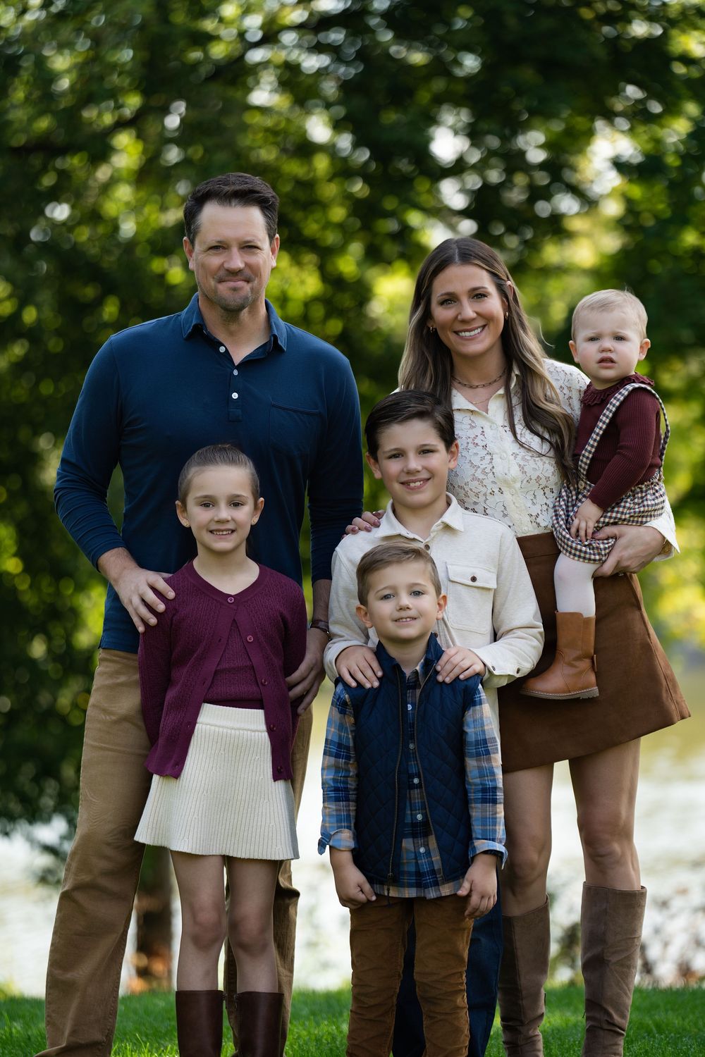 Parents and four children posing together among trees, the mother holding a baby