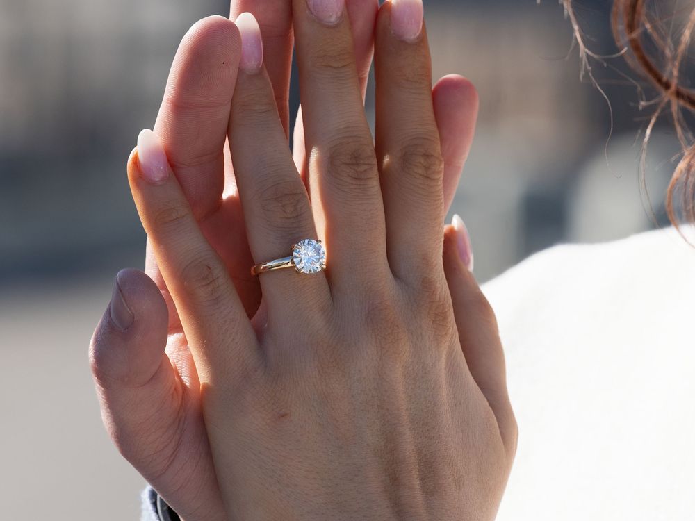 Close-up of a newly engaged woman's hand wearing a round diamond solitaire ring