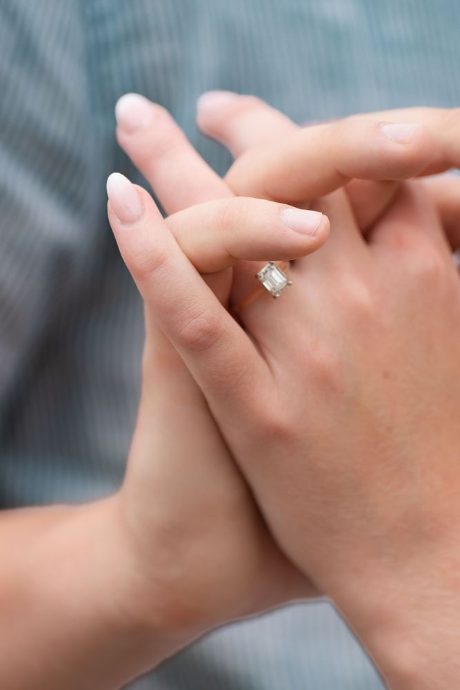 Close-up of clasped hands showing a diamond engagement ring
