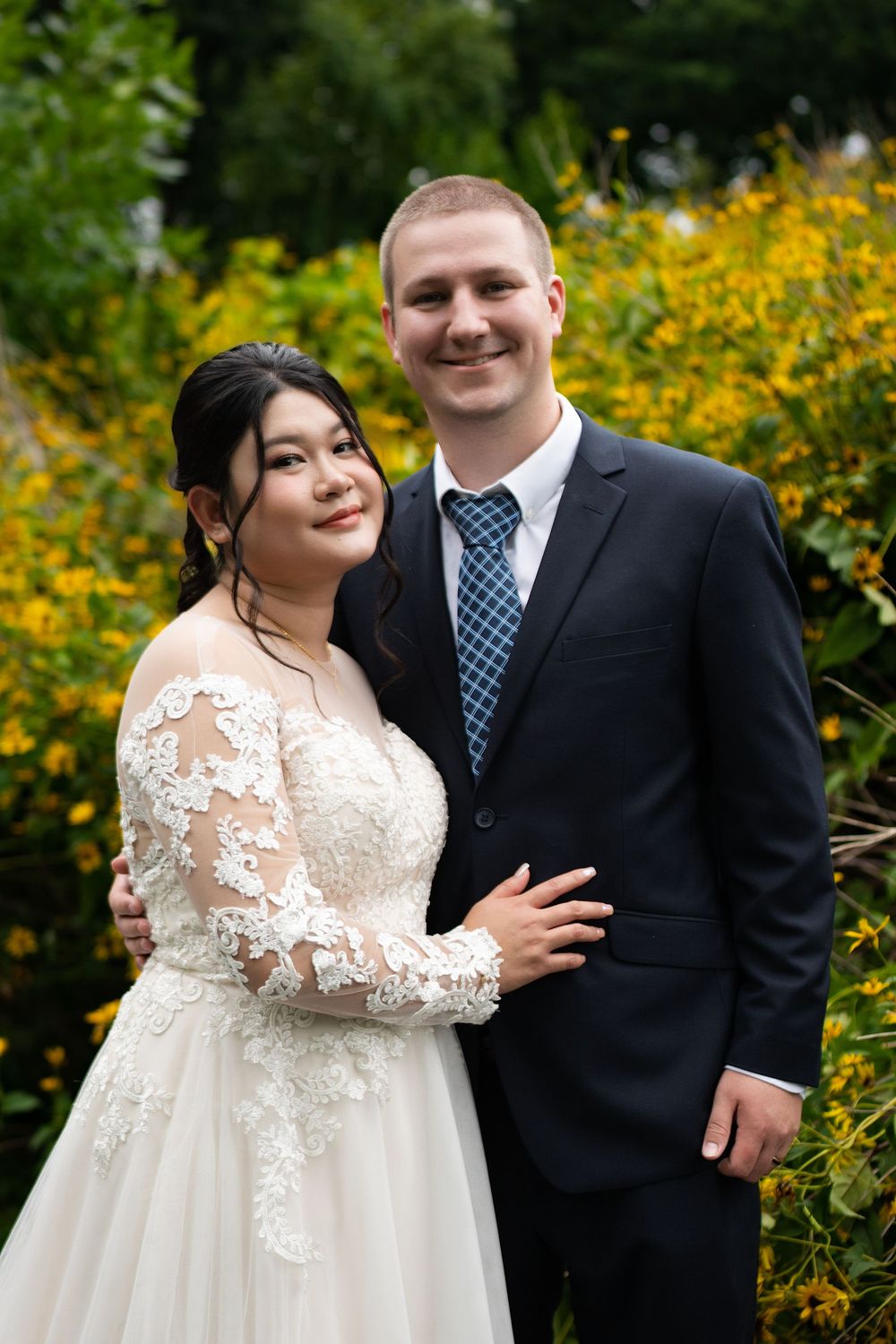 A bride and groom smile together in front of yellow wildflowers