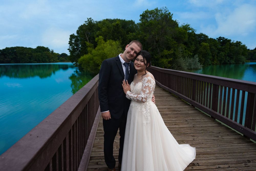 A bride and groom embrace on a wooden boardwalk over a still turquoise lake